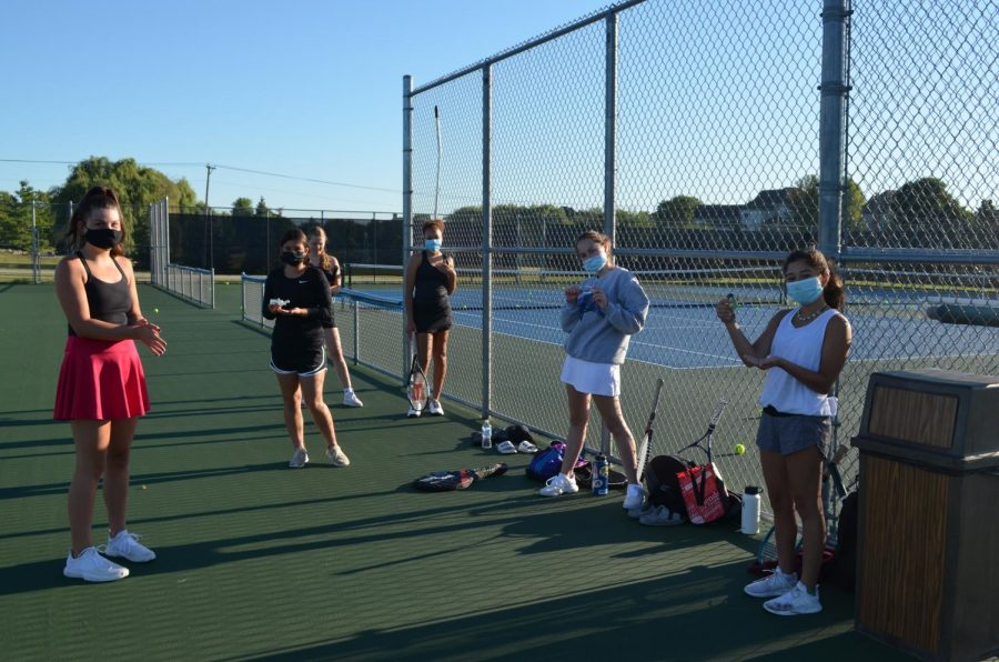 Tennis players apply hand sanitizer in between drills. 