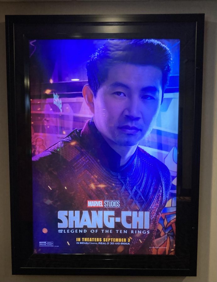 A promotional poster for Shang-Chi and the Legend of the Ten Rings hangs outside a movie theater.