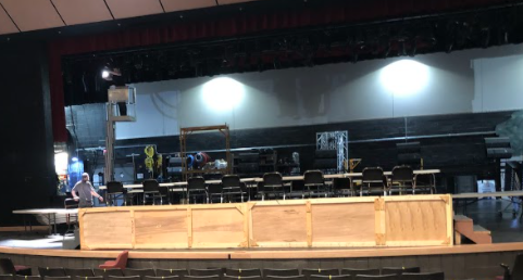 The stage is set up with a high table where the performers sit and the audience sitting on the stage facing them.