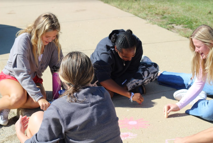 Maya Romanczuk, sophomore, Mekdes Geary, sophomore, and Francie Phillips, sophomore, draw with chalk. 