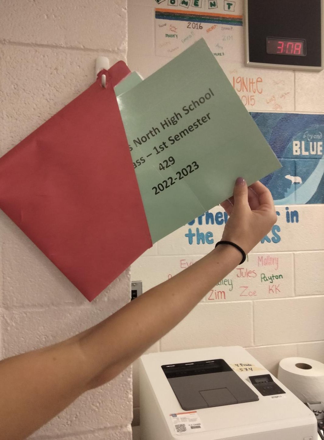 A student reaches for a laminated bathroom pass. 