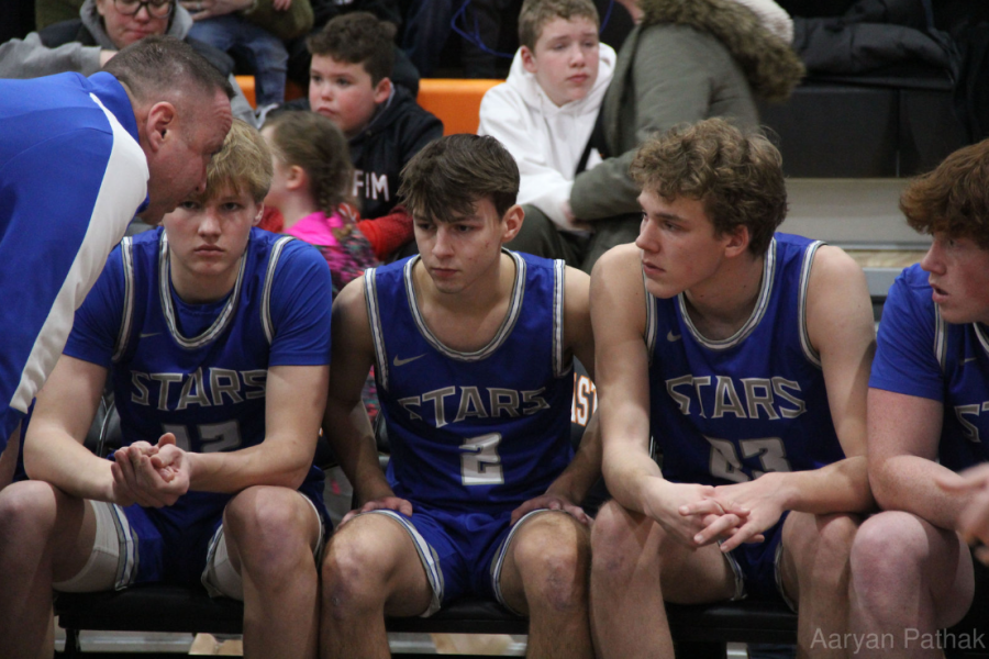 Boys sitting on the sidelines talking to their Coach during game against East