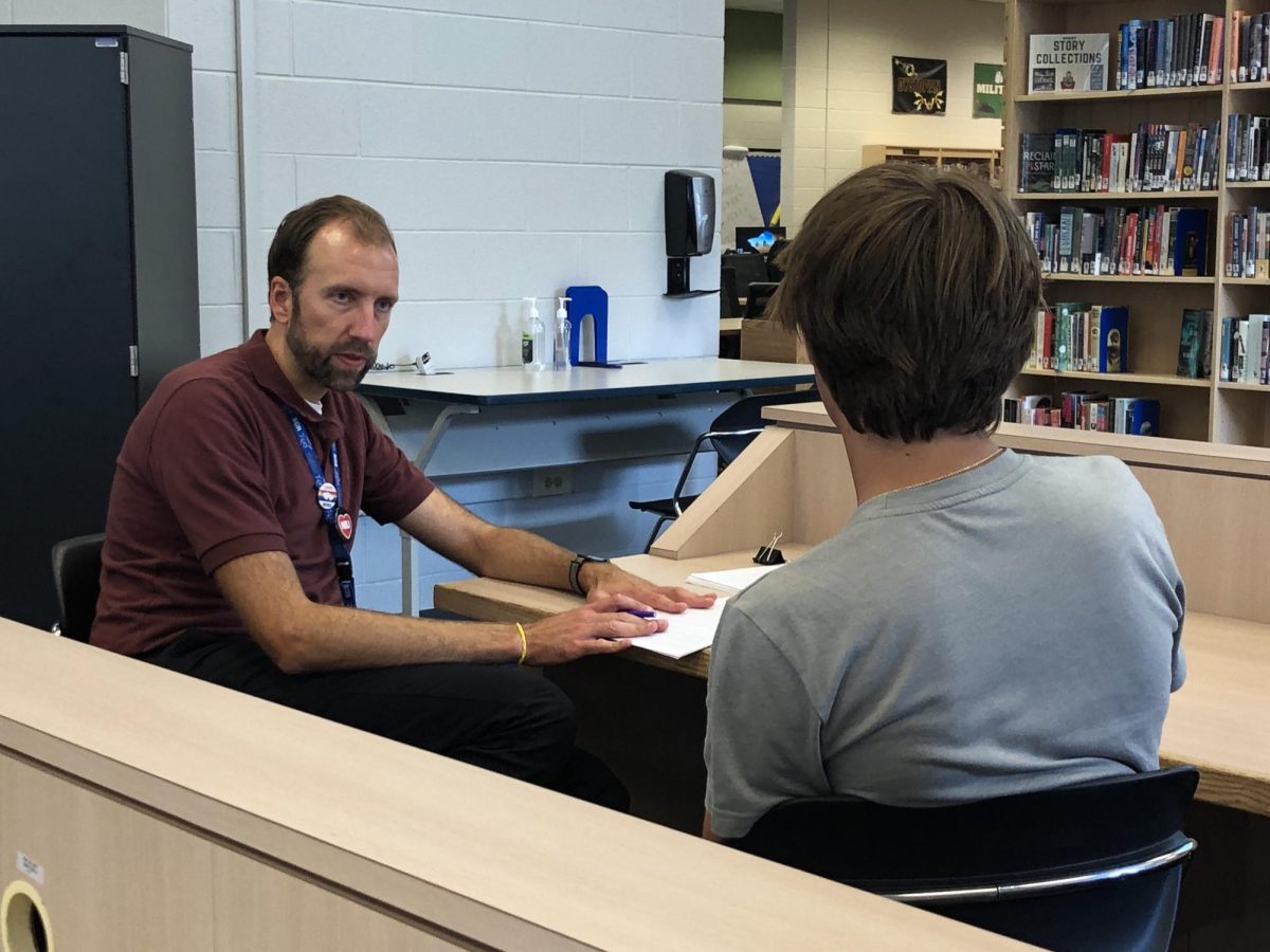 Mr. VonEssen converses with student in makeshift library classroom