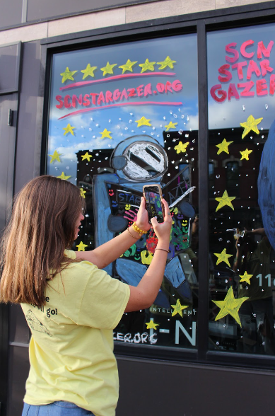Sophomore Tess Arendt taking a picture of a window painting for social media.