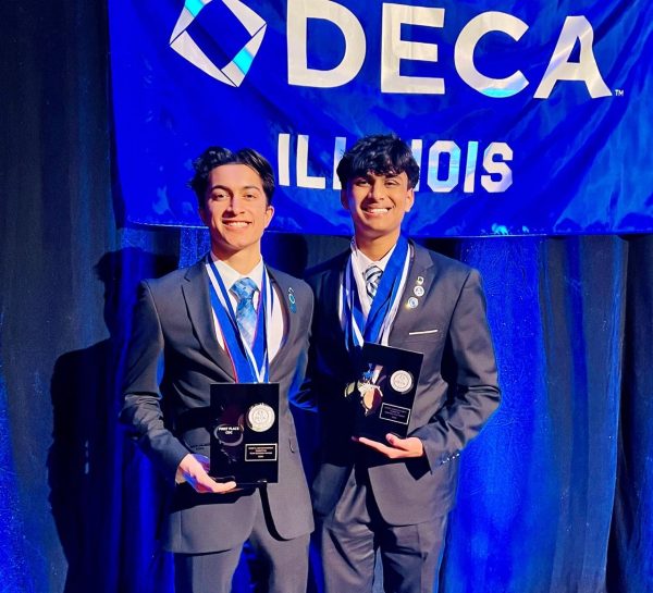 Seniors Keshav Gupta and Dylan Varghese pose after winning first place in sports and entertainment marketing at the DECA state competition.