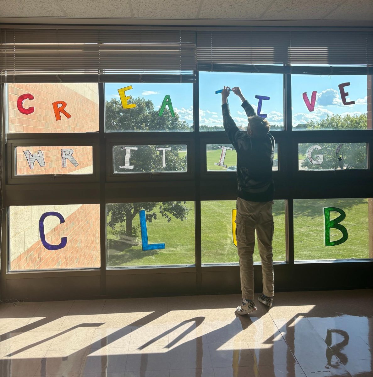 Aiden Kessler, senior, plastering the pod for Creative Writing Club.