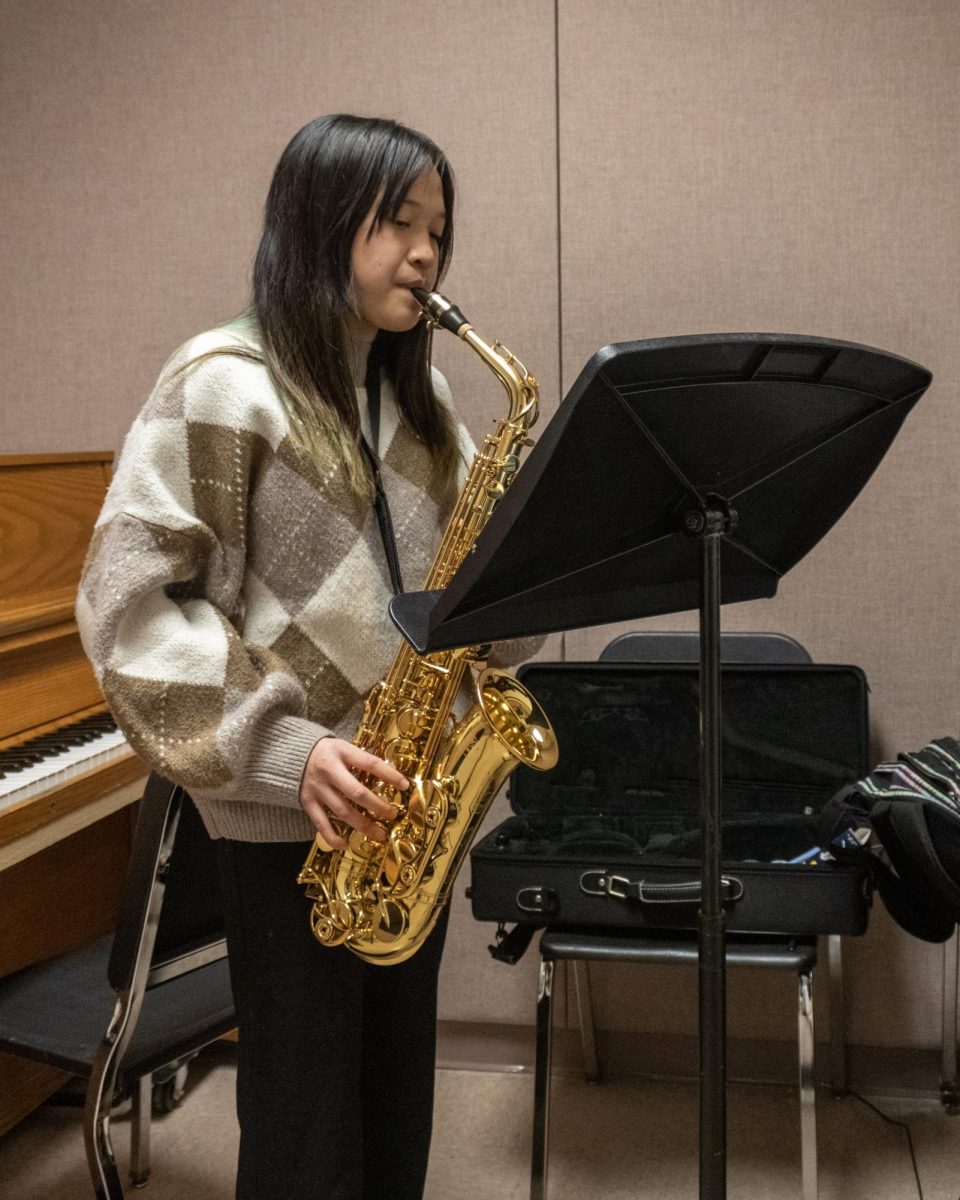 Senior Izzy Tanig playing a  saxophone in one of the practice rooms.
