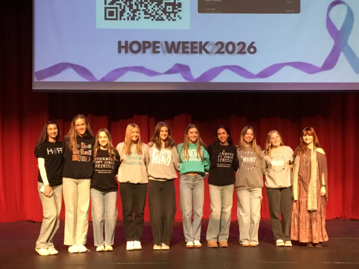 The members of HOPE Club stand on the auditorium stage after one of their presentations.